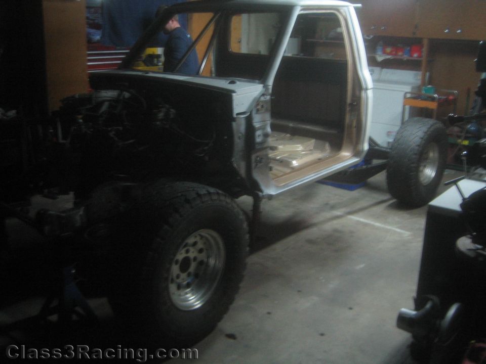 Pickup truck cab on a build stand with suspension fabrication in a garage
