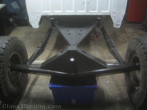 1990 Ford Bronco - Photo of the front of a truck frame and axle setup in a workshop, not a technical document.
