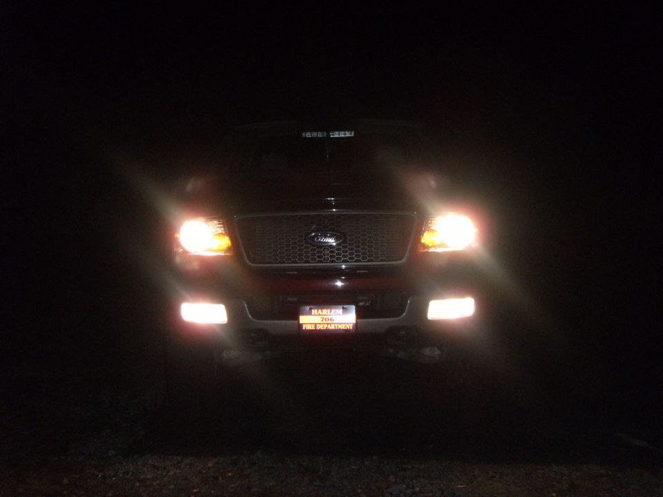 Front of a Ford pickup at night with headlights and fog lights on, Harlem 706 Fire Department plate