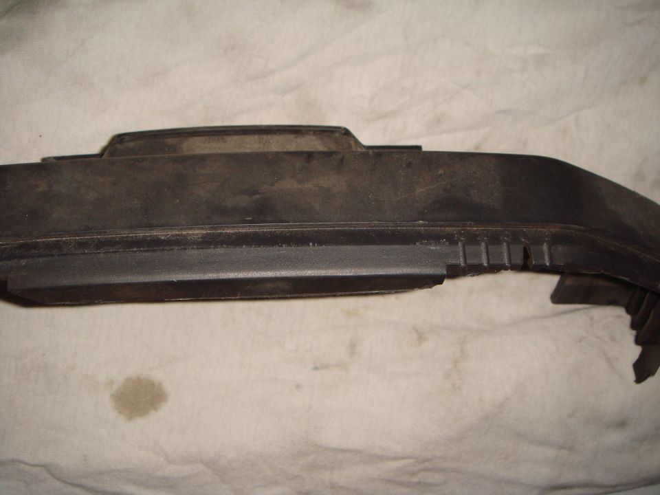 Dusty black plastic automotive trim piece on white cloth