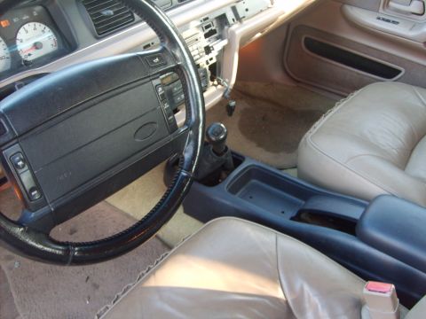 1993 Ford Crown Victoria - The interior of a 1993 Ford Crown Victoria is visible, including the steering wheel, dashboard, and tan seats.
