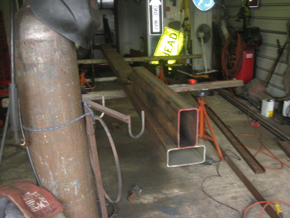 Long steel beam supported on jack stands inside a workshop