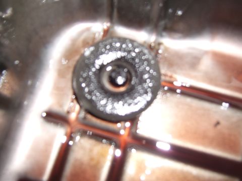 1972 Ford Ranchero - A close-up view of a transmission pan with dark, metallic particulate matter collected on the drain plug magnet.