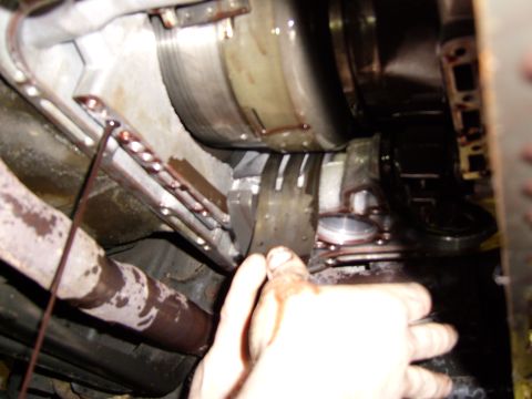 1972 Ford Ranchero - A hand with reddish-brown fluid dripping from it is reaching towards a transmission assembly. The transmission has a torque converter visib…