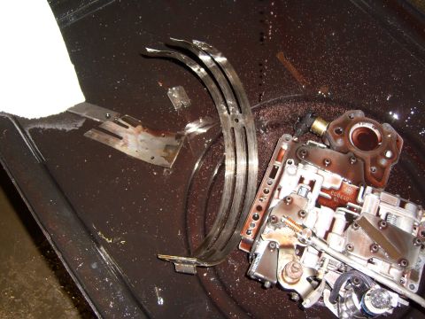1972 Ford Ranchero - A disassembled automatic transmission valve body and clutch pack are shown in a dark pan filled with transmission fluid and debris. Several…