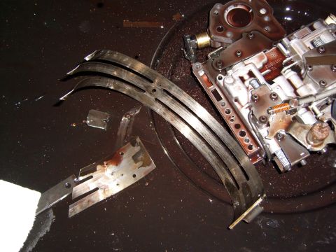 1972 Ford Ranchero - A disassembled automatic transmission valve body and clutch pack components are submerged in dark fluid, likely transmission fluid. Several…