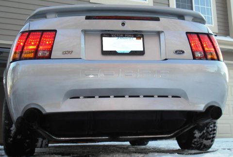 1998 Ford Taurus - The rear view of a silver Ford Mustang Cobra is shown in the snow. The car has a spoiler, dual exhaust pipes, and a license plate frame tha…