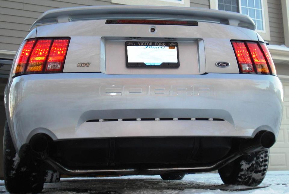 Rear view of a silver Ford Mustang Cobra with dual exhaust and a custom license plate frame.