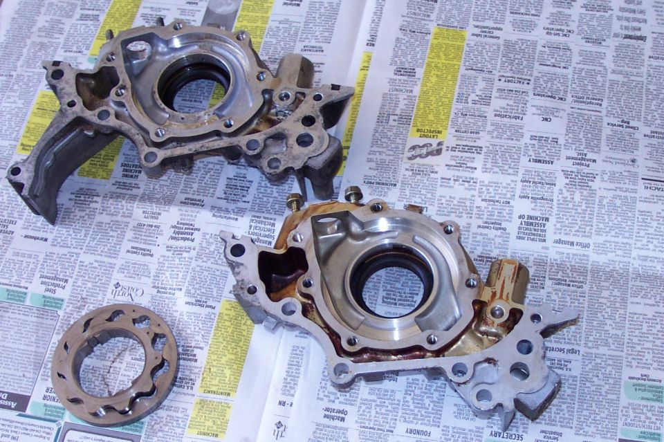 Two disassembled engine oil pump housings on newspaper