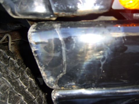 1972 Ford Ranchero - A close-up, low-angle shot shows the rear bumper and tire of a dark-colored vehicle. The bumper appears to be chrome or a dark metallic fin…