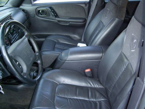 1972 Ford Ranchero - The interior of a vehicle shows black leather seats, a steering wheel with a Dodge logo, and a center console with an armrest.
