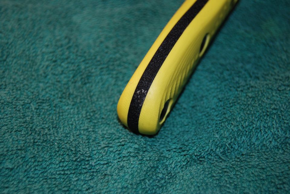 Yellow tool handle with black grip on teal textured surface.