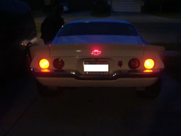 Rear view of a white Chevrolet Camaro with illuminated brake lights.