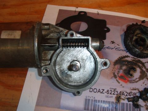 1994 Ford Bronco - A disassembled motor and gears are laid out on a paper with part numbers visible. The motor housing is made of metal and shows signs of wea…