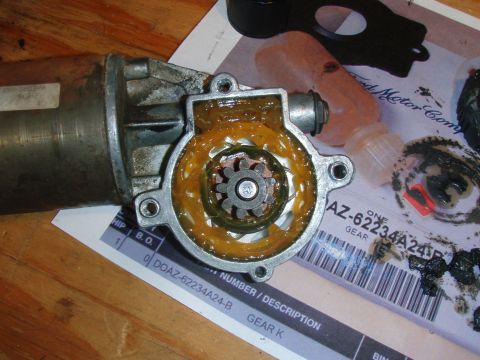 1994 Ford Bronco - A disassembled starter motor with its gear housing filled with yellow grease is shown. A part of the motor's cylindrical body is visible on…