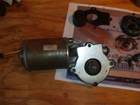 1994 Ford Bronco - A disassembled power window motor assembly is shown on a wooden surface, with a paper document indicating it is for a 1994 Ford Bronco.