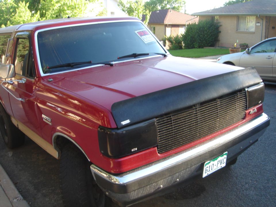 Red 1994 Ford Bronco front view with black bug deflector and Colorado license plate.