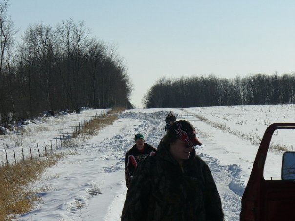 People on a snowy road with trees and a fence line