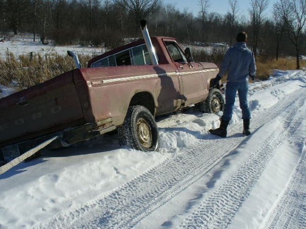 Side view of a maroon 1978 Ford F-150 stuck in snow with dual exhaust pipes