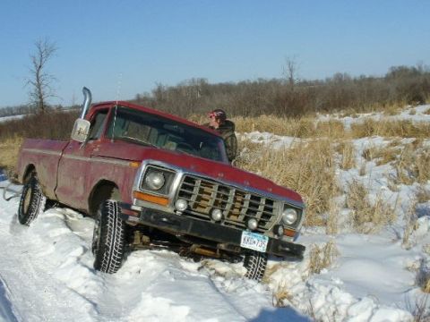 1978 Ford F-150 - A red 1978 Ford F-150 is stuck in a snowy ditch with dry grass around it.