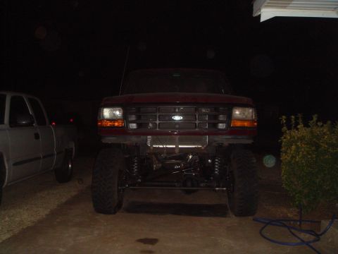 1992 Ford Bronco - A lifted 1992 Ford Bronco is parked in front of a house at night, with a silver pickup truck to its left.