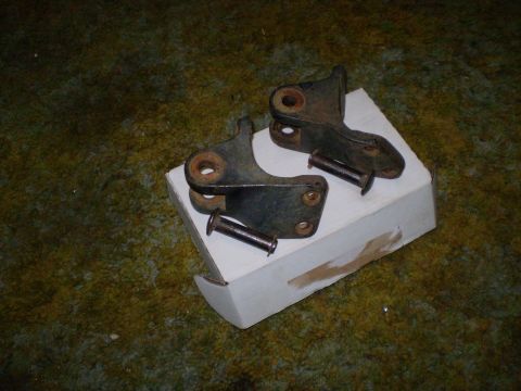 2005 Ford Excursion - Two rusty metal brackets and pins are shown on a white box.