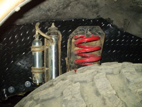 1978 Ford Bronco - The suspension system, including a red coil spring and shock absorber, is visible next to a large off-road tire.