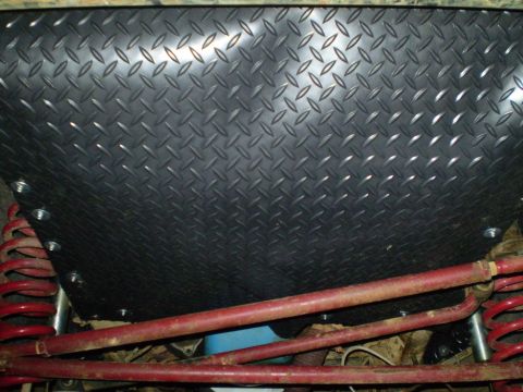 1978 Ford Bronco - Diamond plate panel installed over vehicle suspension components, showing red springs and bars.