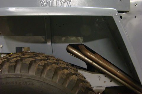 1948 Jeep Wrangler - Close-up of the rear wheel well area of a gray Jeep CJ-5, showing dual exhaust pipes and "WILLYS" badging.