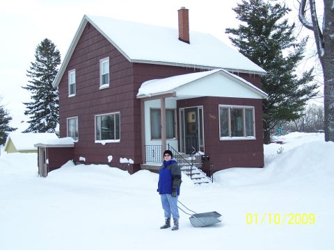 1989 Ford F-150 - A house stands in the snow with a person and a shovel in the foreground.