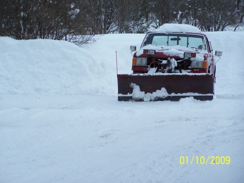 1989 Ford F-150 - A red pickup truck equipped with a snow plow is seen in a snowy environment, outdoor environment.