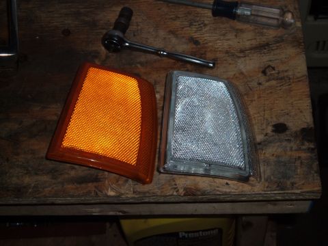 1990 Ford Ranger - Two vehicle corner light assemblies, one amber and one clear, lie on a workbench next to a ratchet and screwdriver.