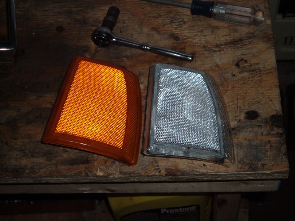 Orange and clear corner light assemblies on a wooden surface with tools