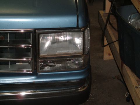 1990 Ford Ranger - The front corner of a blue 1990 Ford Ranger is visible, showing its clear turn signal and chrome grille.