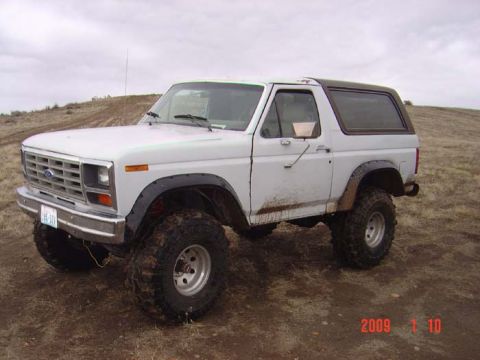 1983 Ford Bronco - This Ford Bronco is shown from a three-quarter front angle, parked outdoors on a dirt terrain.