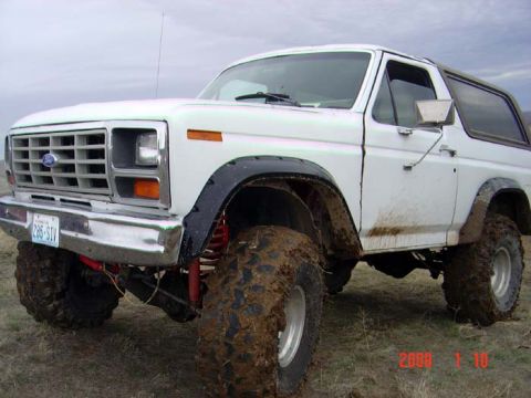 1983 Ford Bronco - This 1983 Ford Bronco is equipped with large off-road tires, showing signs of recent use in muddy conditions.