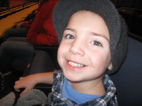 1994 Ford Bronco - A young boy smiles while sitting in the stands, with a partial view of an 'Advance Auto Parts' sign in the background.