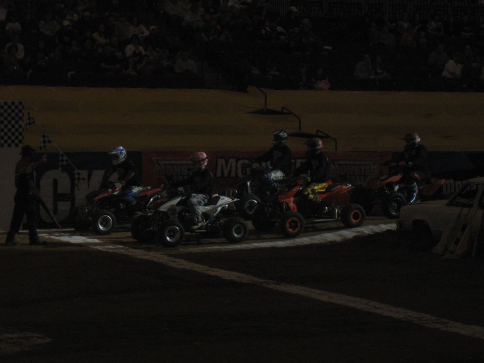 Four-wheelers lined up at a starting line with a checkered flag