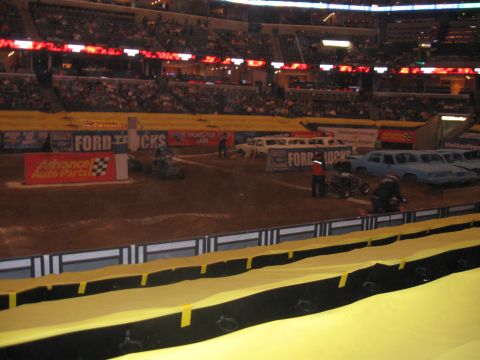 1994 Ford Bronco - Monster Jam event with several cars lined up on the dirt arena floor.