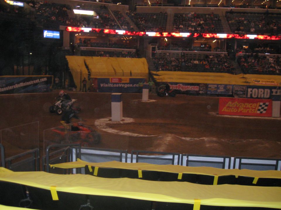 Monster truck in arena with ATVs and crowd