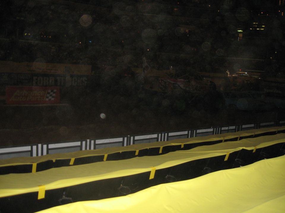 Monster truck arena with yellow tarp covering seats and Ford Trucks sign in background