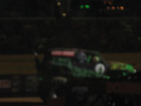 1994 Ford Bronco - A monster truck with distinctive green and black graphics is seen from the side, likely at an event.