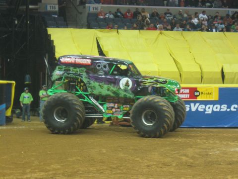 1994 Ford Bronco - Monster truck Grave Digger is on display at an indoor event with spectators in the background.