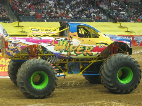 1994 Ford Bronco - Monster truck with viper graphics and green rims is shown in an arena.