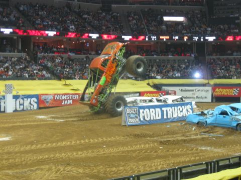 1994 Ford Bronco - Monster truck performs a jump over a line of crushed cars during a Monster Jam event.