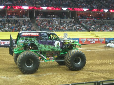 1994 Ford Bronco - A monster truck with the Grave Digger theme is displayed in an arena with spectators in the background.