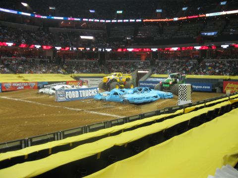 1994 Ford Bronco - Monster Jam event with monster trucks poised to crush cars in an arena.