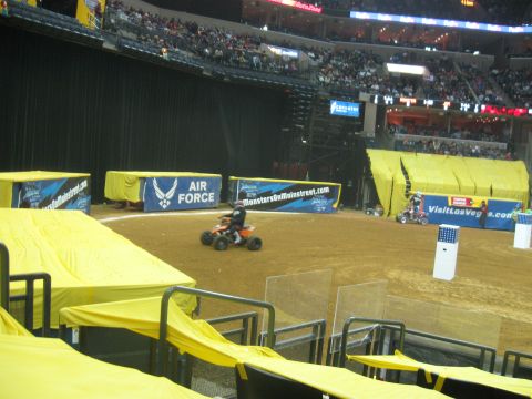 1994 Ford Bronco - An ATV rider navigates a dirt arena during an event, with various sponsor banners visible.