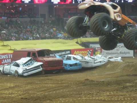 1994 Ford Bronco - Monster truck performs a jump over wrecked cars during a Monster Jam event.