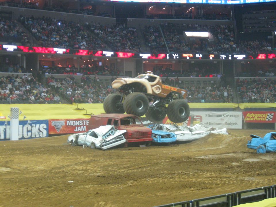 Monster truck jumps over crushed cars at Monster Jam event